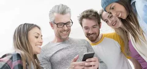 Five Individuals Look at Cell Phone Protected by a Network Security Solution