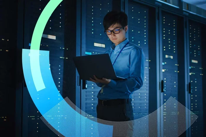 Engineer managing servers in data center with laptop.**