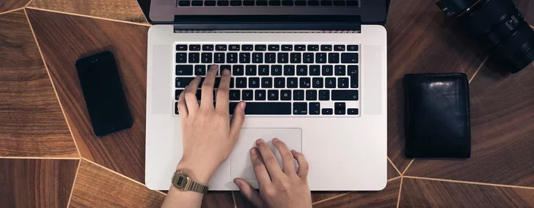 Top down view of someone typing at a Macbook