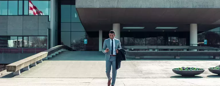 Businessman in a suit looking at his smartphone while walking