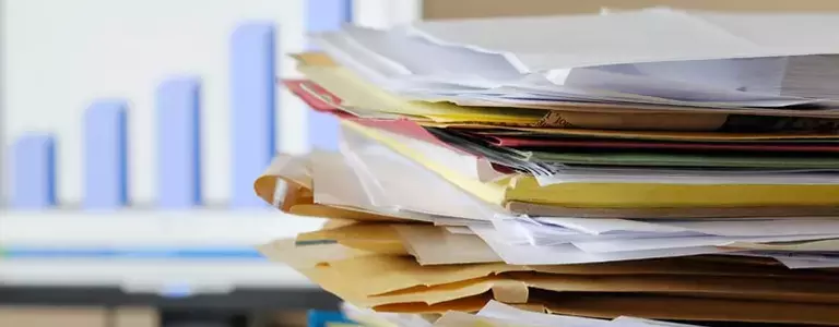 Stack of papers and folders with a graph in the background