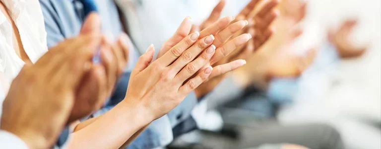 Colleagues applauding at a meeting honoring a person