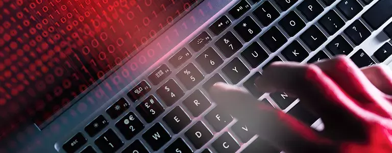 Hand typing on a Macbook with glowing red binary