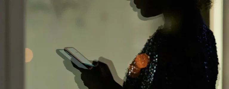 Blurry photo of the silhouette of a woman looking at her smartphone