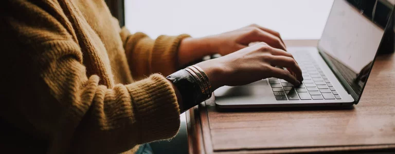 Woman sitting at a desk typing on her laptop