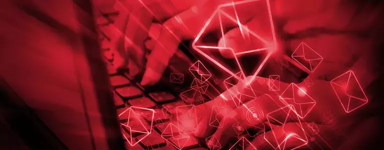 Hands typing with red email icons floating in the foreground