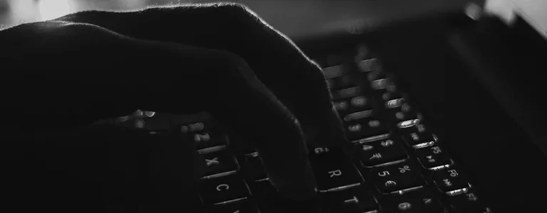Darkened closeup of someone typing on a laptop
