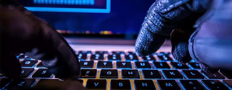 Closeup of gloved hands typing on a laptop