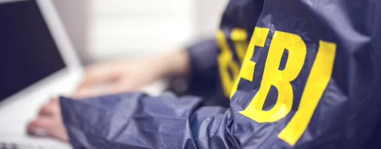 Person in an FBI windbreaker using a laptop