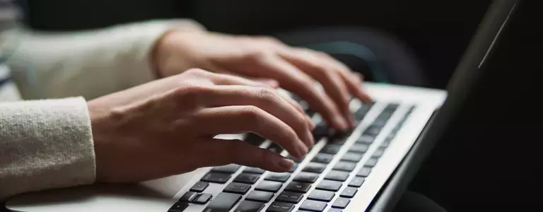 Hands typing on a Macbook keyboard