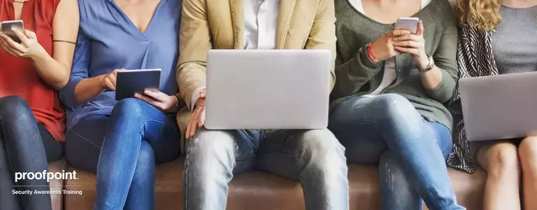 Coworkers sharing a couch while using their electronic devices