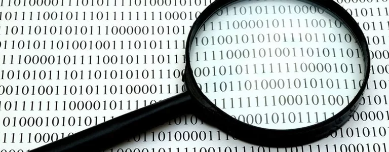 Magnifying glass laying on a page of binary code