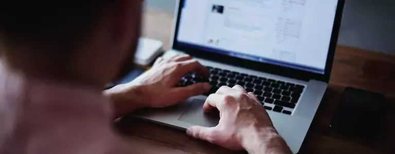 Man using his laptop sitting at a desk