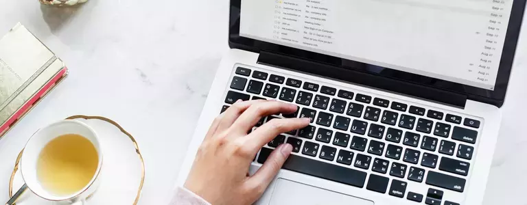 Hand typing on a macbook keyboard at work