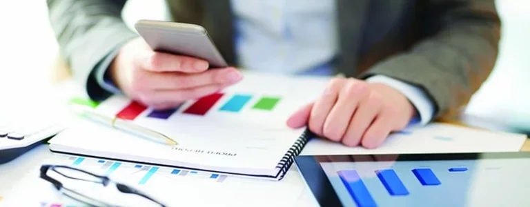 Business Person using their smartphone and looking at bar charts