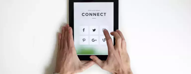 Hands holding a tablet showing social media app icons