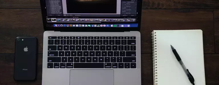 Smartphone, laptop, notebook, and pen on a desk