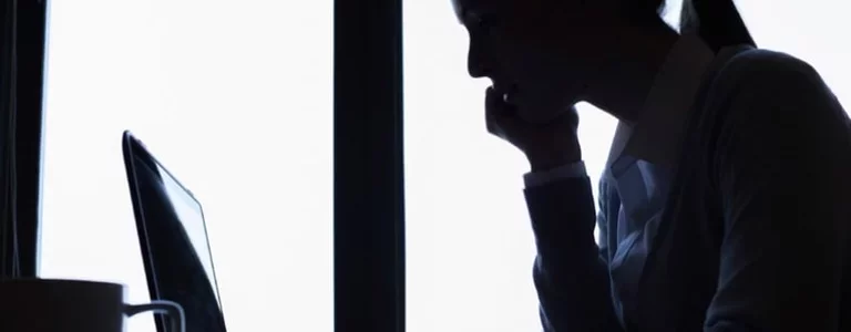 silhouette employee at her computer at her desk