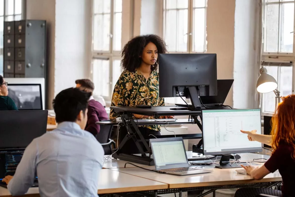 Security analysts working in a modern office environment, reviewing dashboards and data on multiple monitors—representing Proofpoint teams monitoring threats and protecting users.