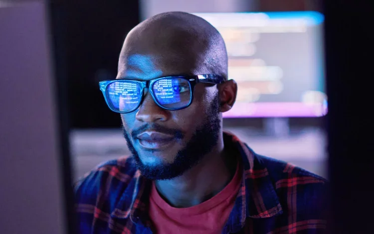 Close-up of analyst focused on screen with code reflected.